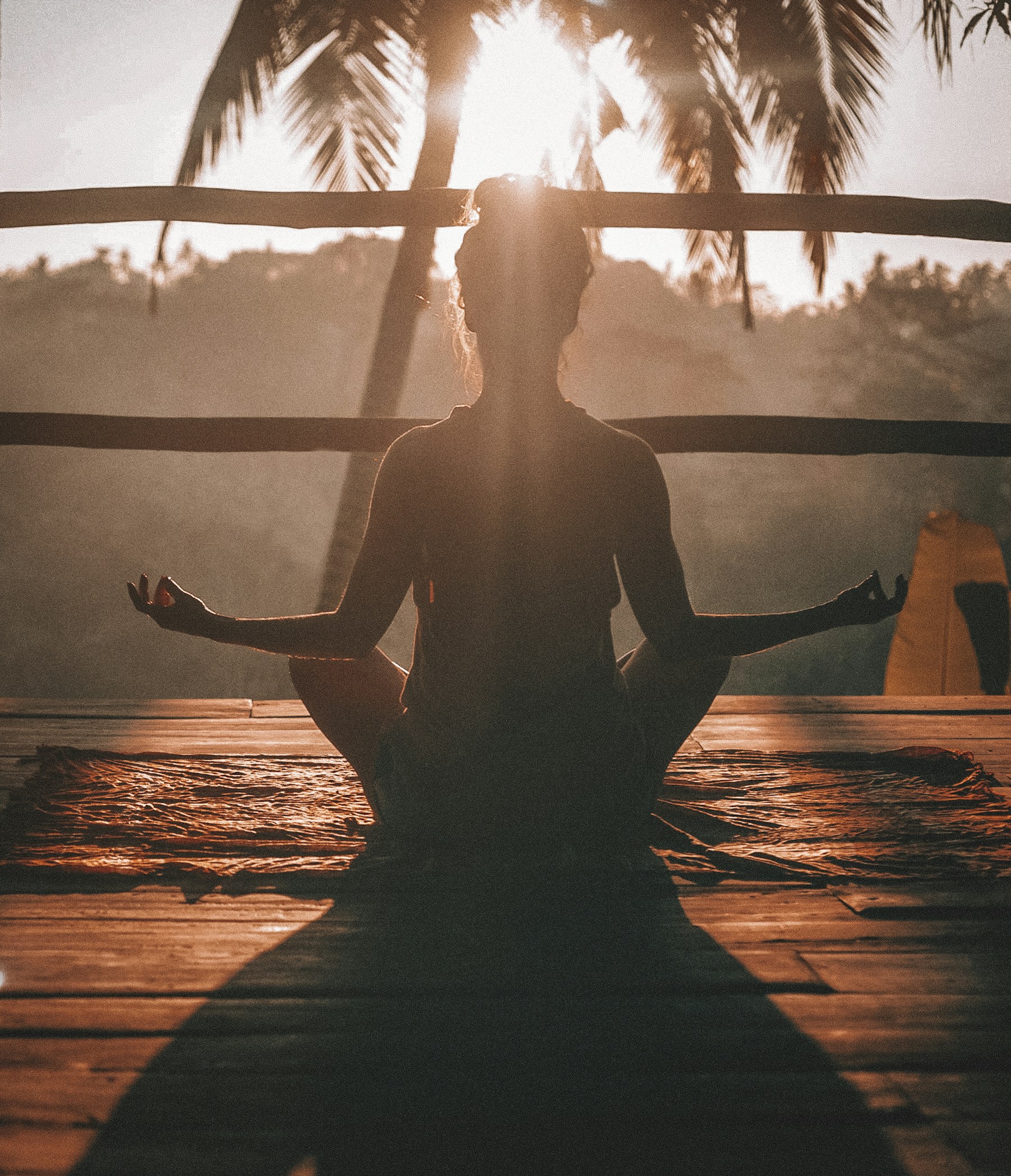 Mujer meditando en un espacio de yoga bañado por la luz cálida del atardecer